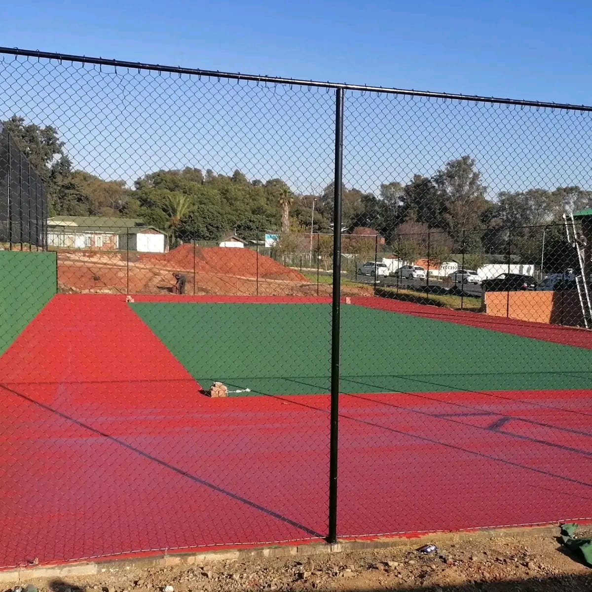 Fresh red and green coated surface behind black chain-link fencing
