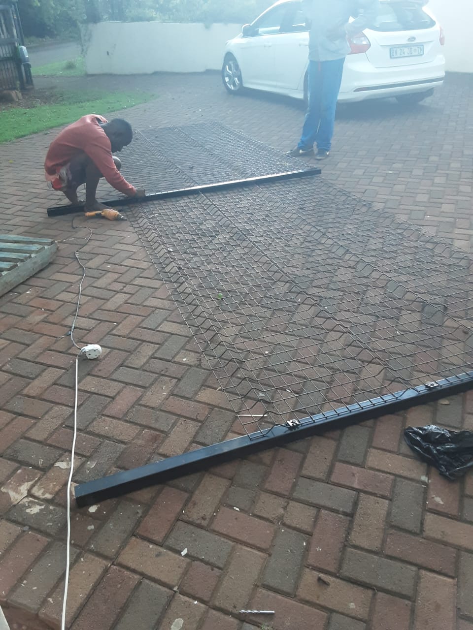 Diamond mesh gate panel being assembled on a paved driveway