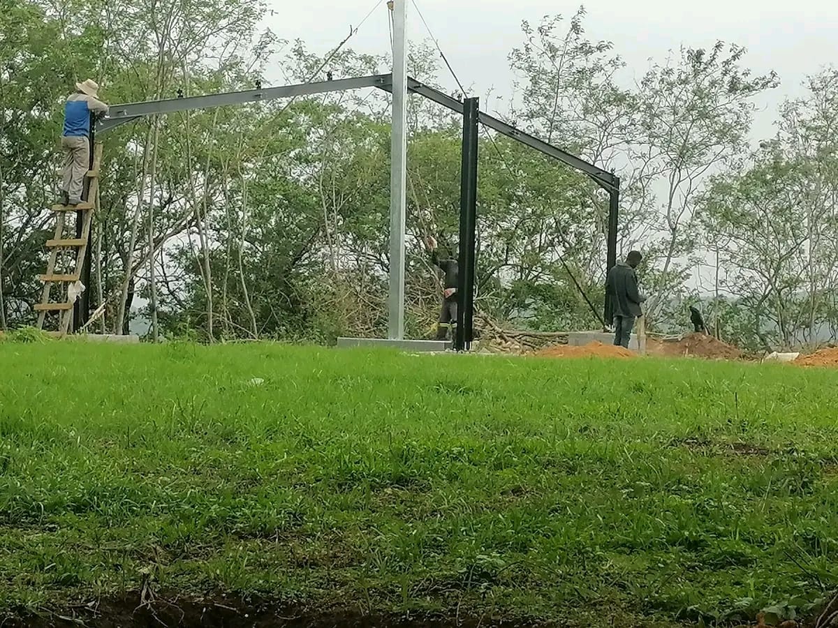 Construction workers installing a steel frame structure on a hillside site