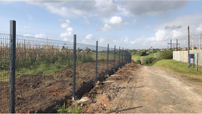 Long roadside fence installed beside a gravel access road